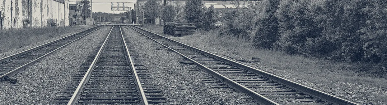 Railroad tracks running toward a vanishing point through industrial Baltimore